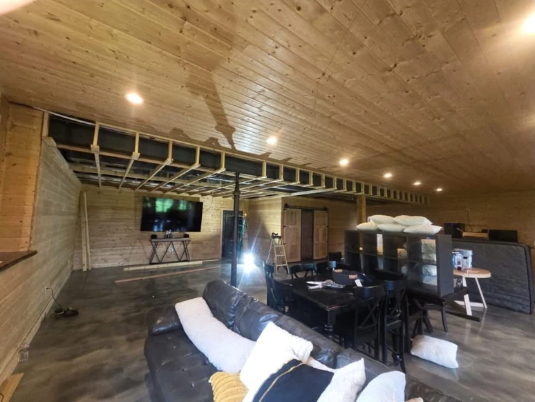 A wide view of an interior with wood ceiling boards and a framed drop-ceiling section.